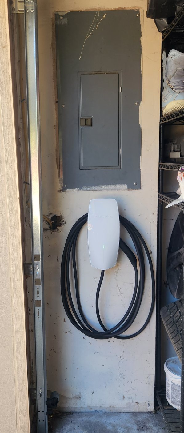 Tesla Wall Connector installed beside the panel in a garage